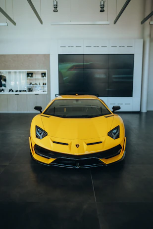 A bright yellow hatchback displayed in a minimalist, well-lit showroom.