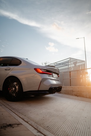A sleek modern car parked in front of a vibrant Tunisian cityscape at sunset.