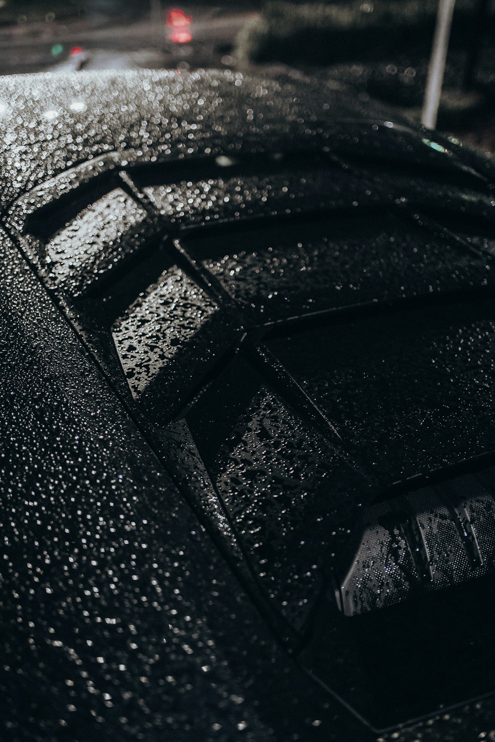 a close up of a black car with rain drops on it