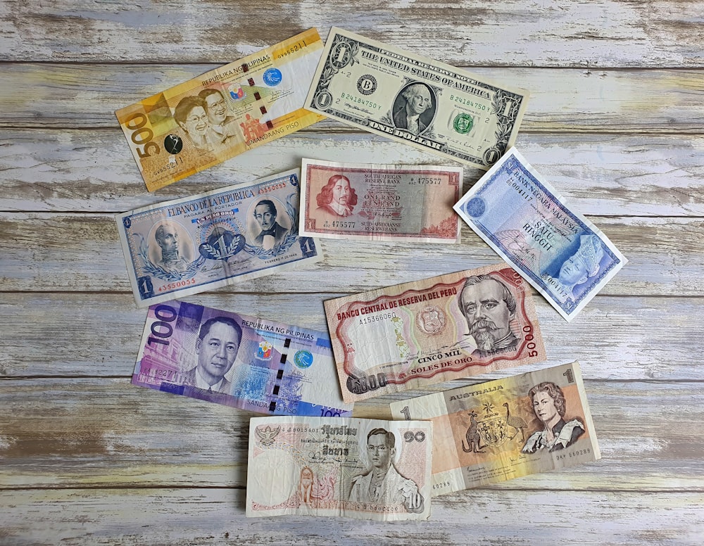 a bunch of different currency sitting on top of a wooden table