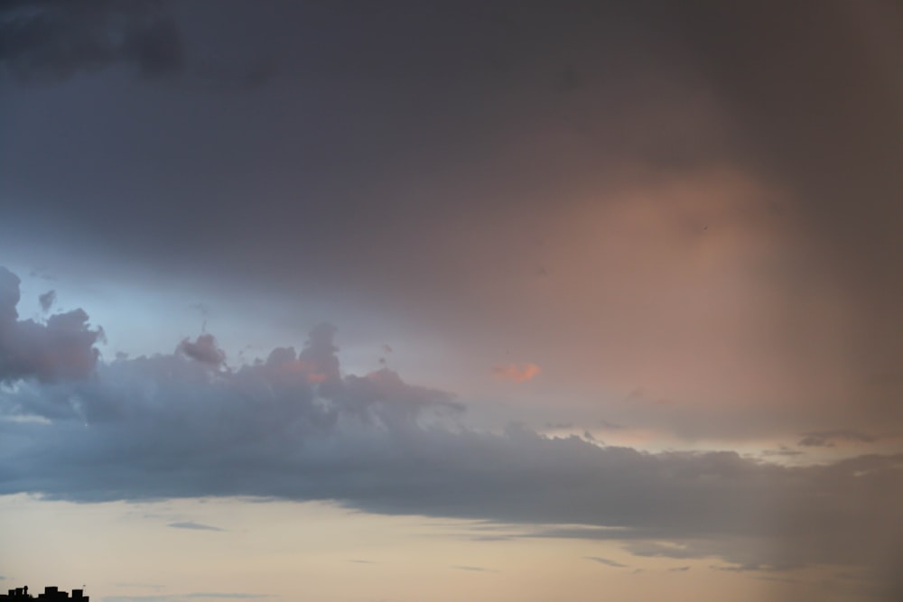 a cloudy sky with a plane in the foreground