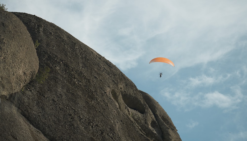 a paraglider is flying over a rocky cliff