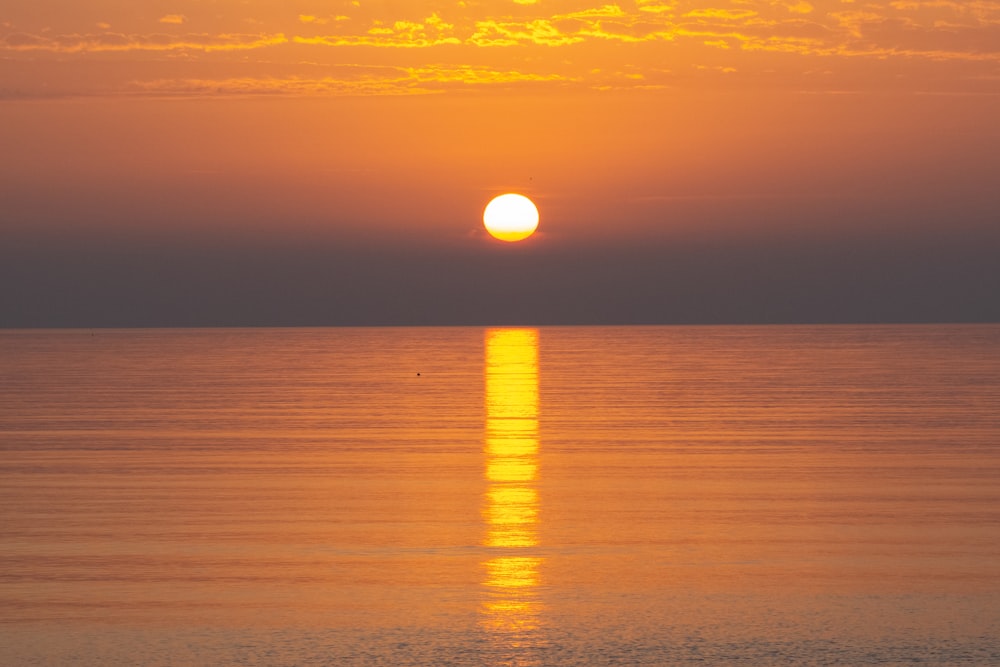 a large body of water with a sunset in the background