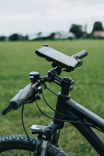 A cyclist attaching a phone mount to a bicycle handlebar outdoors