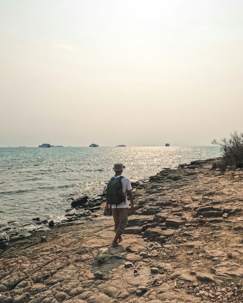 un homme debout sur une plage à côté de l’océan