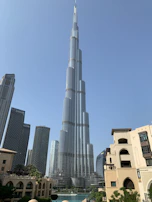 The towering Burj Khalifa piercing the clear blue sky in Dubai, surrounded by modern skyscrapers.