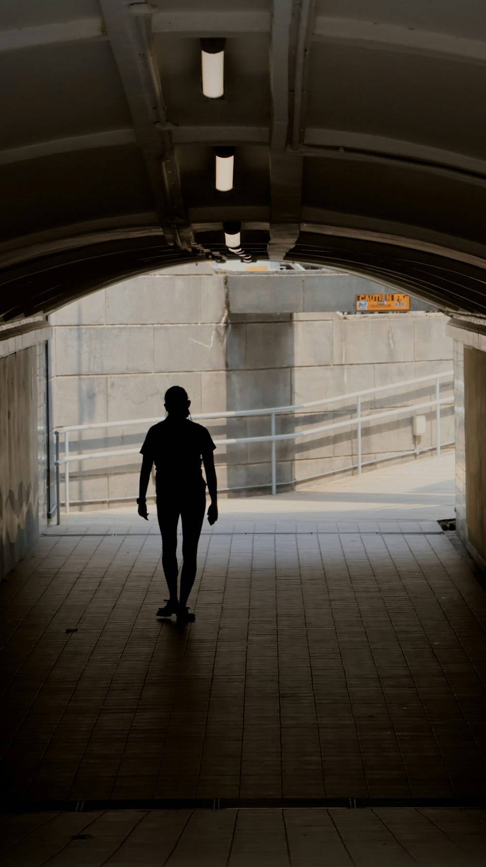 a person walking through a tunnel with a skateboard