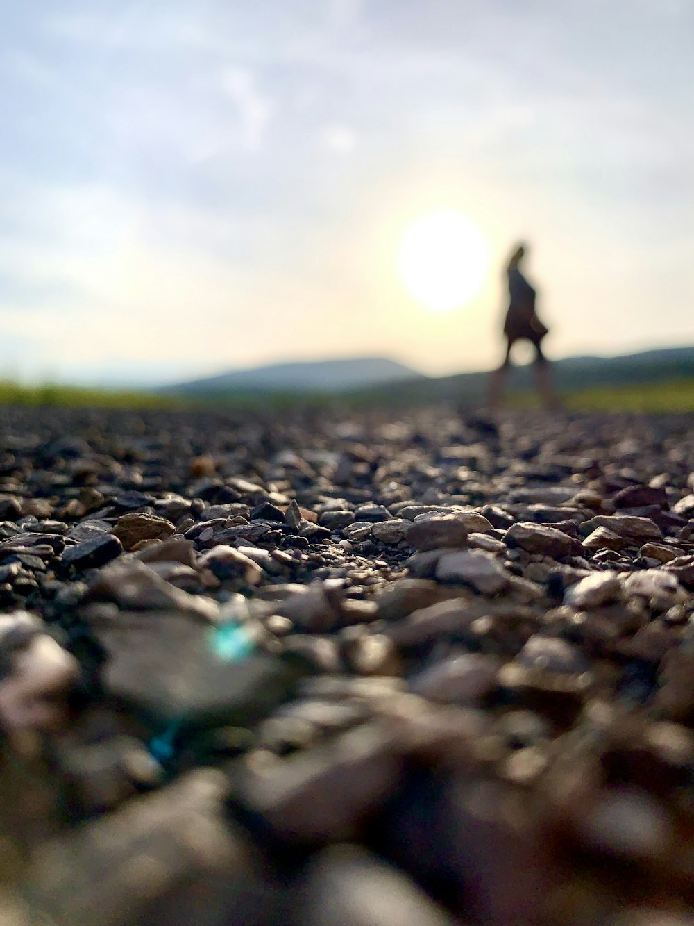 a person standing on a rocky road with the sun in the background