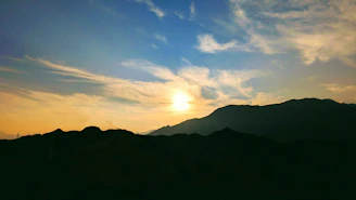 A scenic landscape with mountains in the distance at sunset.