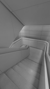 A modern, minimalistic staircase with smooth, curving lines and a sleek, monochrome design. The walls and railings are integrated into the architectural structure, creating a seamless look.
