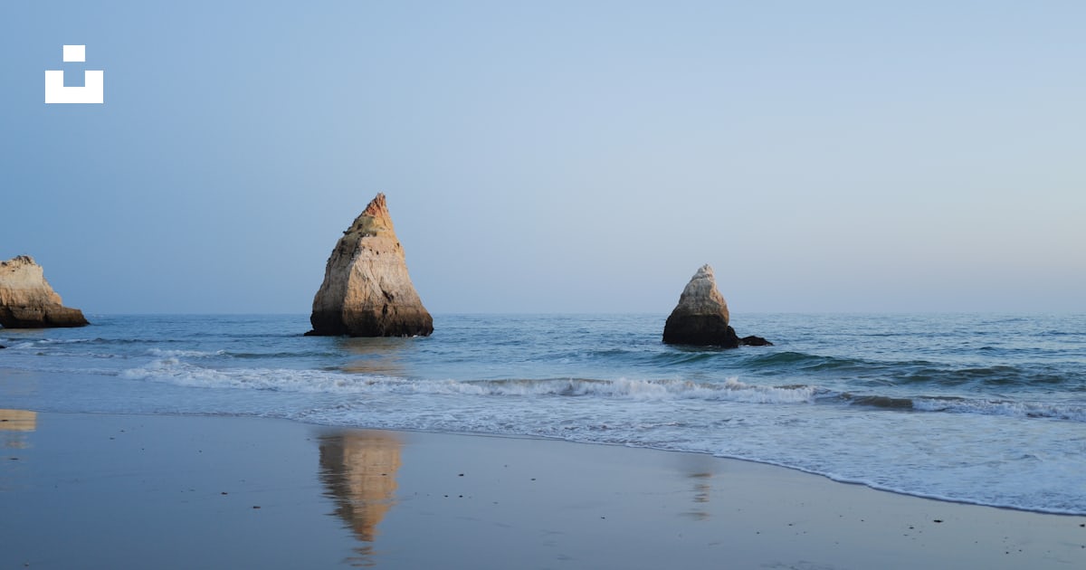 Tres rocas que sobresalen del agua en una playa foto – Imagen de ...