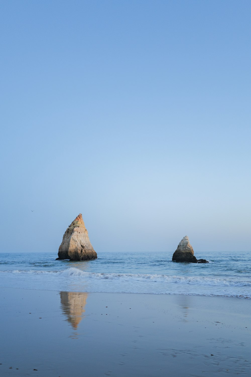 a large rock sitting on top of a beach next to the ocean