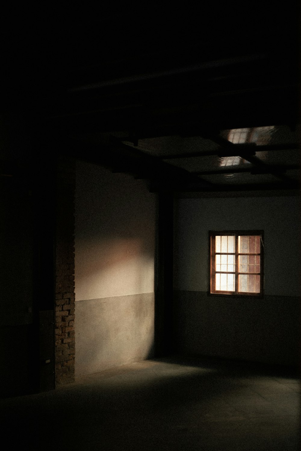 a dark room with a window and a brick wall