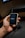 A hand is holding a small, portable electronic device with a screen displaying the word 'ACTIVO'. The device is connected to a black cable.