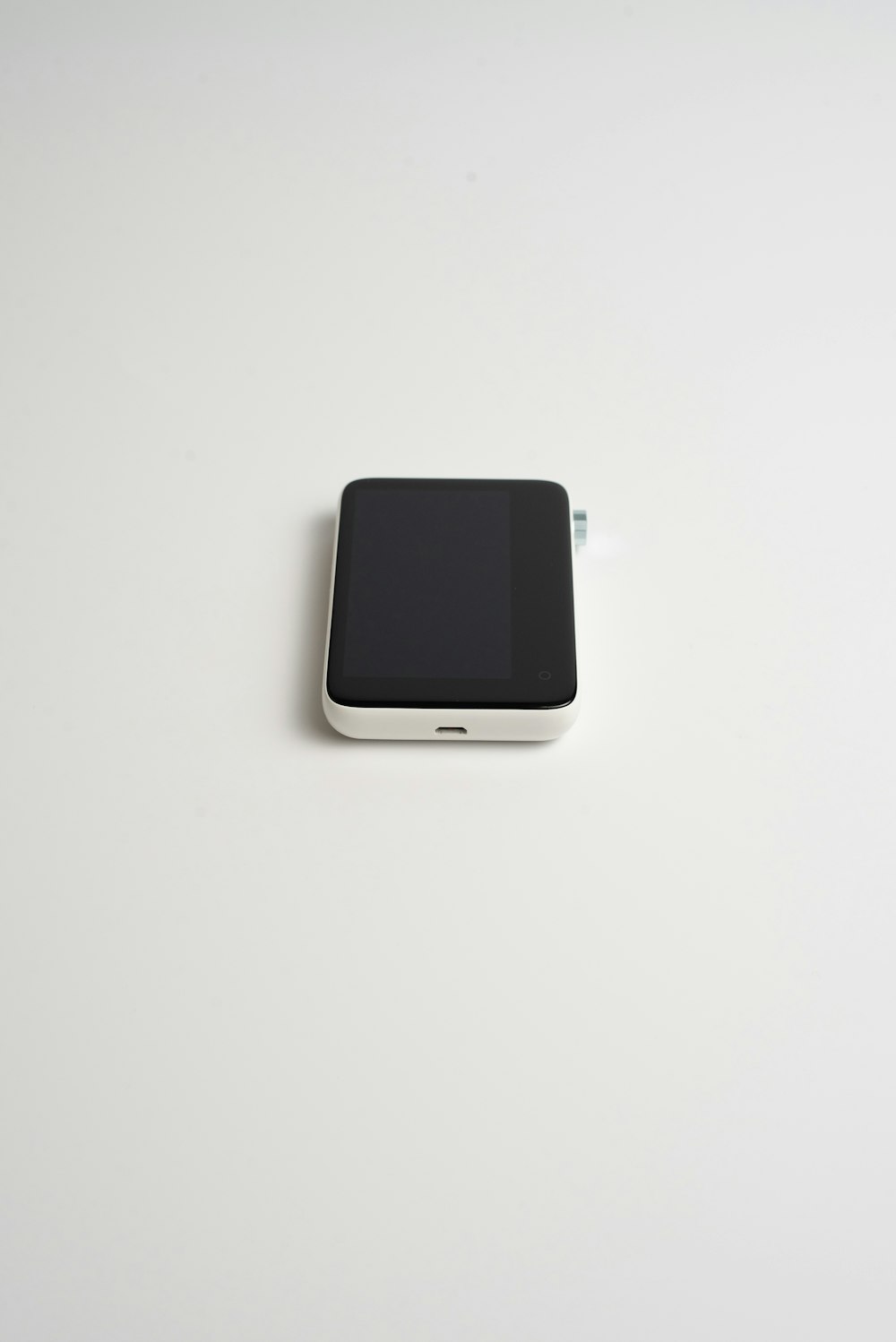 a black and white cell phone sitting on a white surface