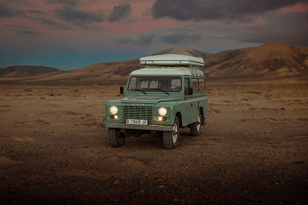 Une camionnette verte garée au milieu d’un désert