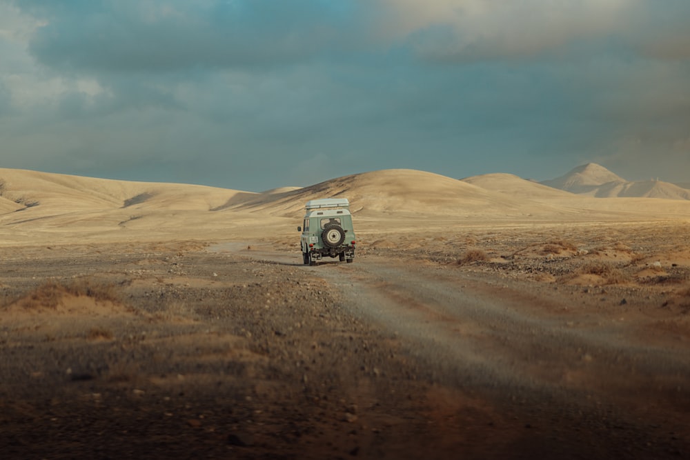 a truck driving down a dirt road in the desert