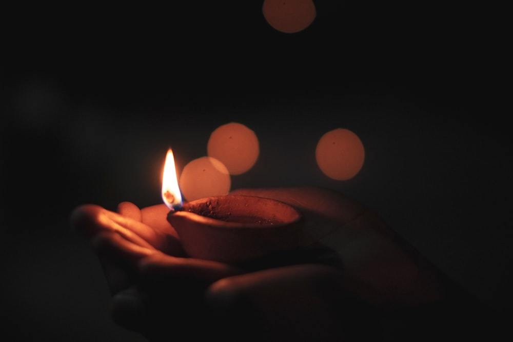 a person holding a lit candle in their hand