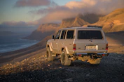 A rugged SUV climbing a rocky terrain with a sunset background, emphasizing durability and power.
