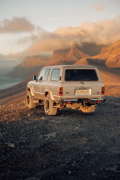 A male overlander navigating a rocky mountain path with his van under warm golden hour light.