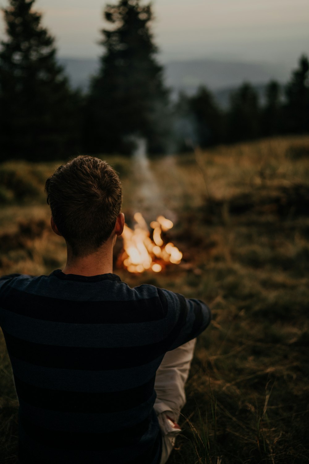 a man sitting in front of a campfire