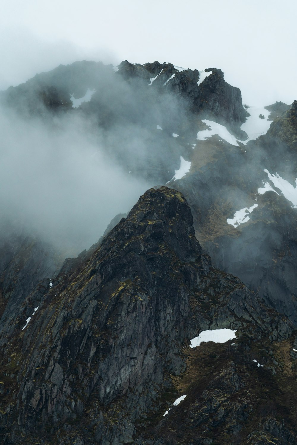 a very tall mountain covered in snow and clouds