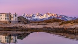 Evening view of an earthquake-resistant prefab home glowing warmly against the charcoal grey mountain backdrop.