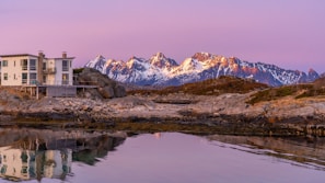 Evening view of an earthquake-resistant prefab home glowing warmly against the charcoal grey mountain backdrop.