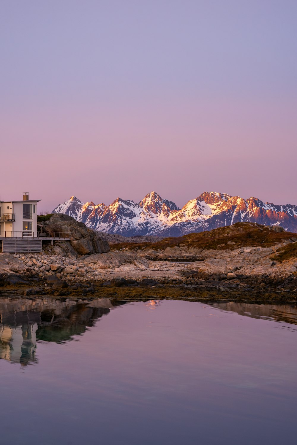 a house sitting on top of a mountain next to a body of water