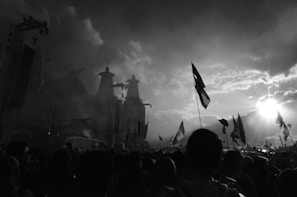 A vibrant crowd gathered under a bright sky, hands raised in worship during an outdoor crusade.