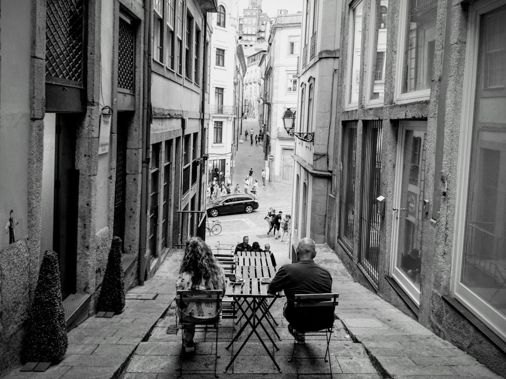 two people sitting at a table in an alleyway