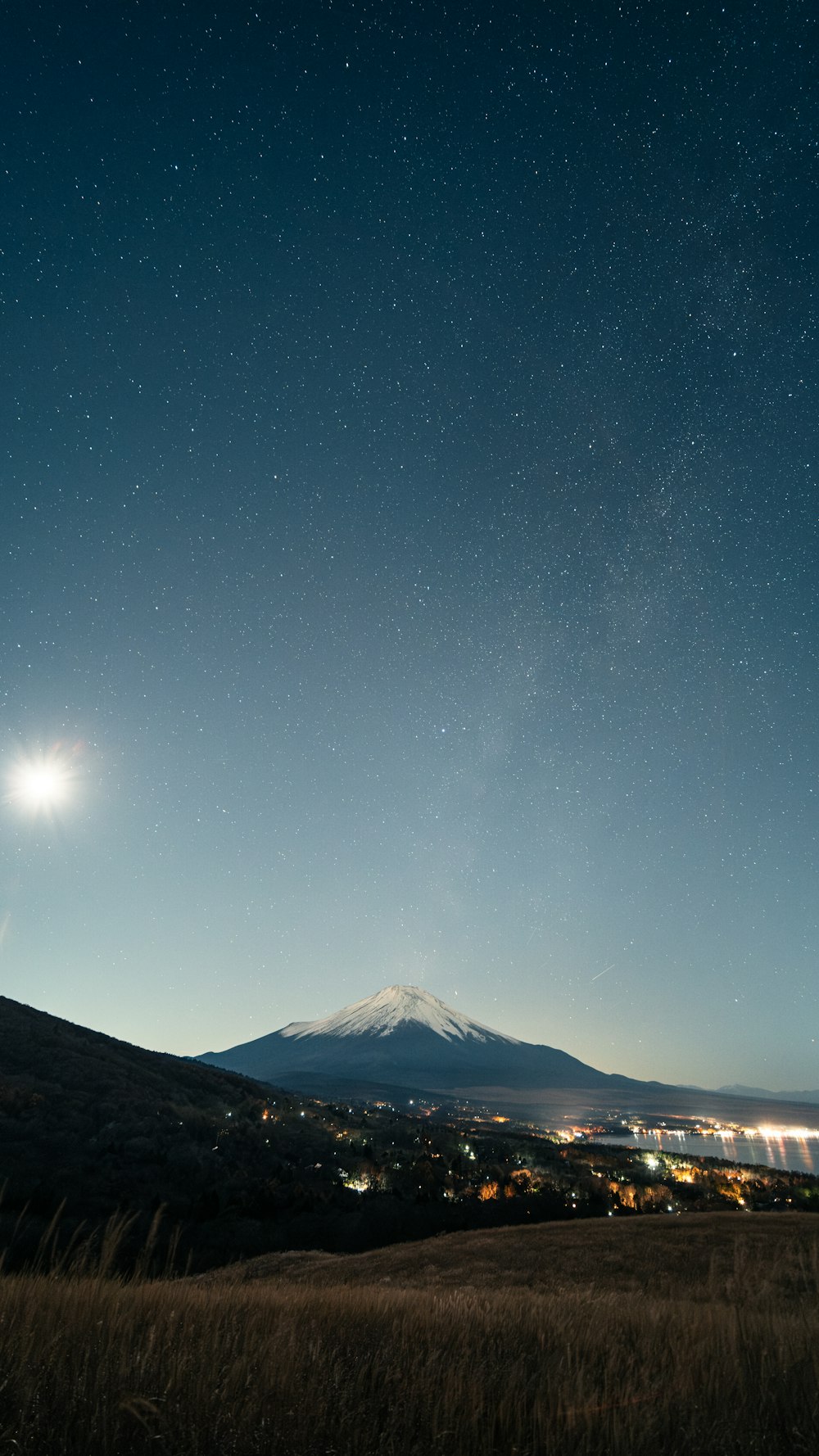 une vue du ciel nocturne avec une montagne en arrière-plan