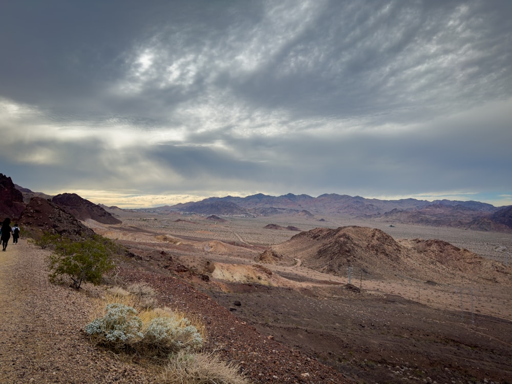 a couple of people walking down a dirt road