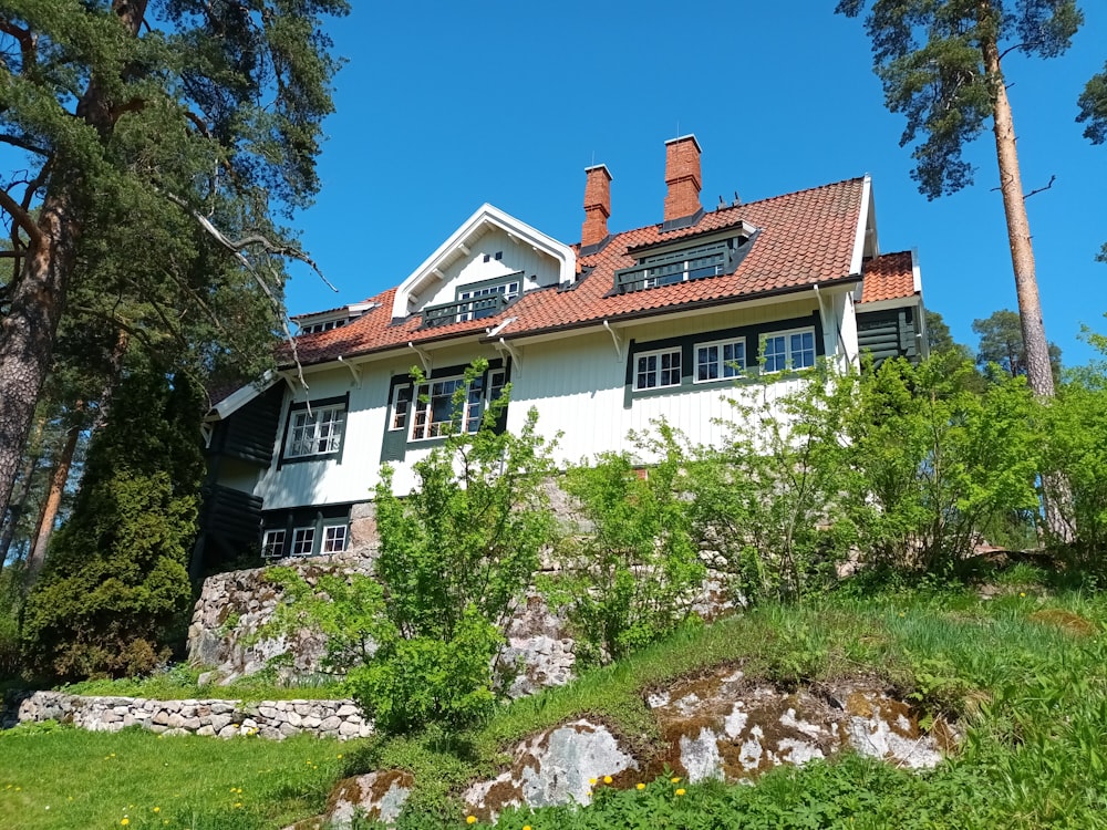 a white house with a red roof surrounded by trees