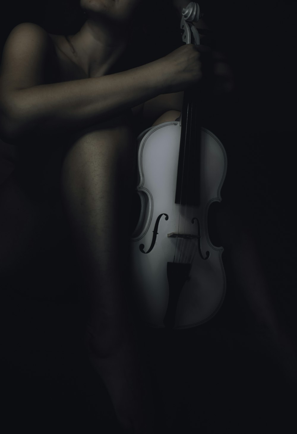 a woman holding a violin in the dark