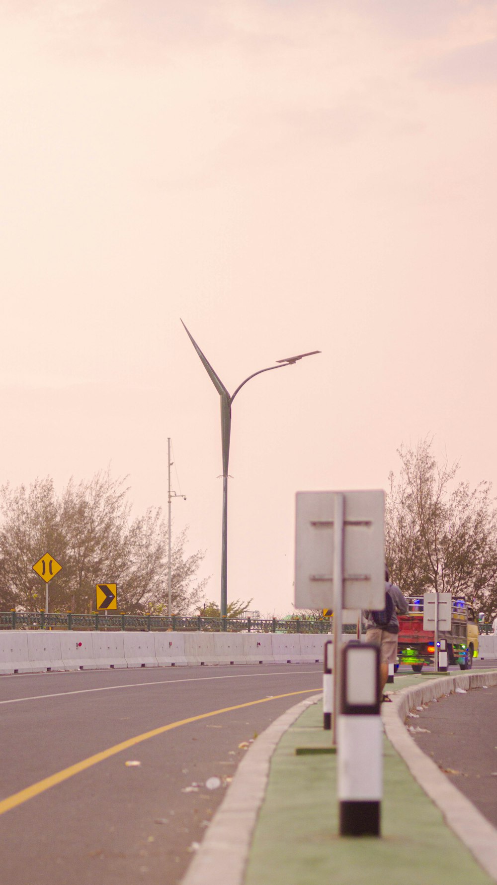 a street with a street sign and a wind turbine in the background