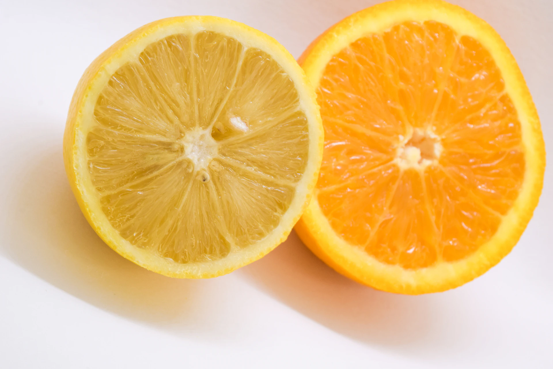 two halves of a lemon and an orange on a white background