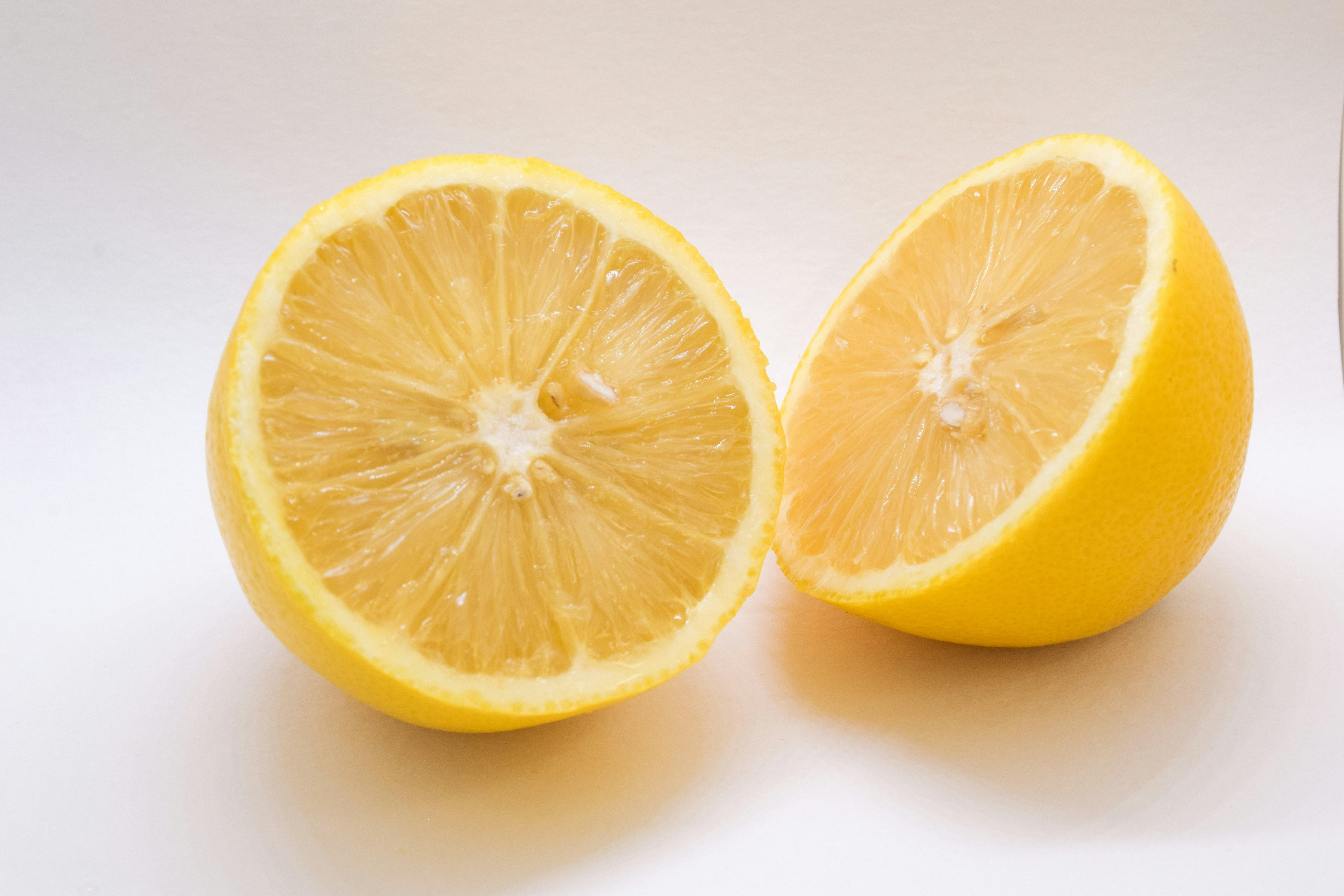 two lemons cut in half on a white surface