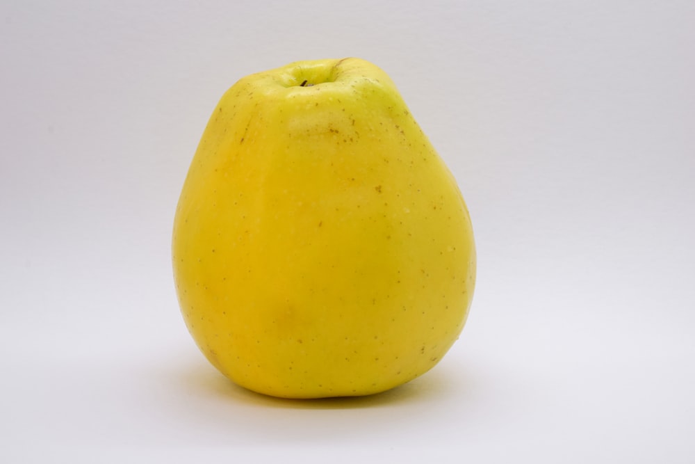 a yellow apple sitting on top of a white table