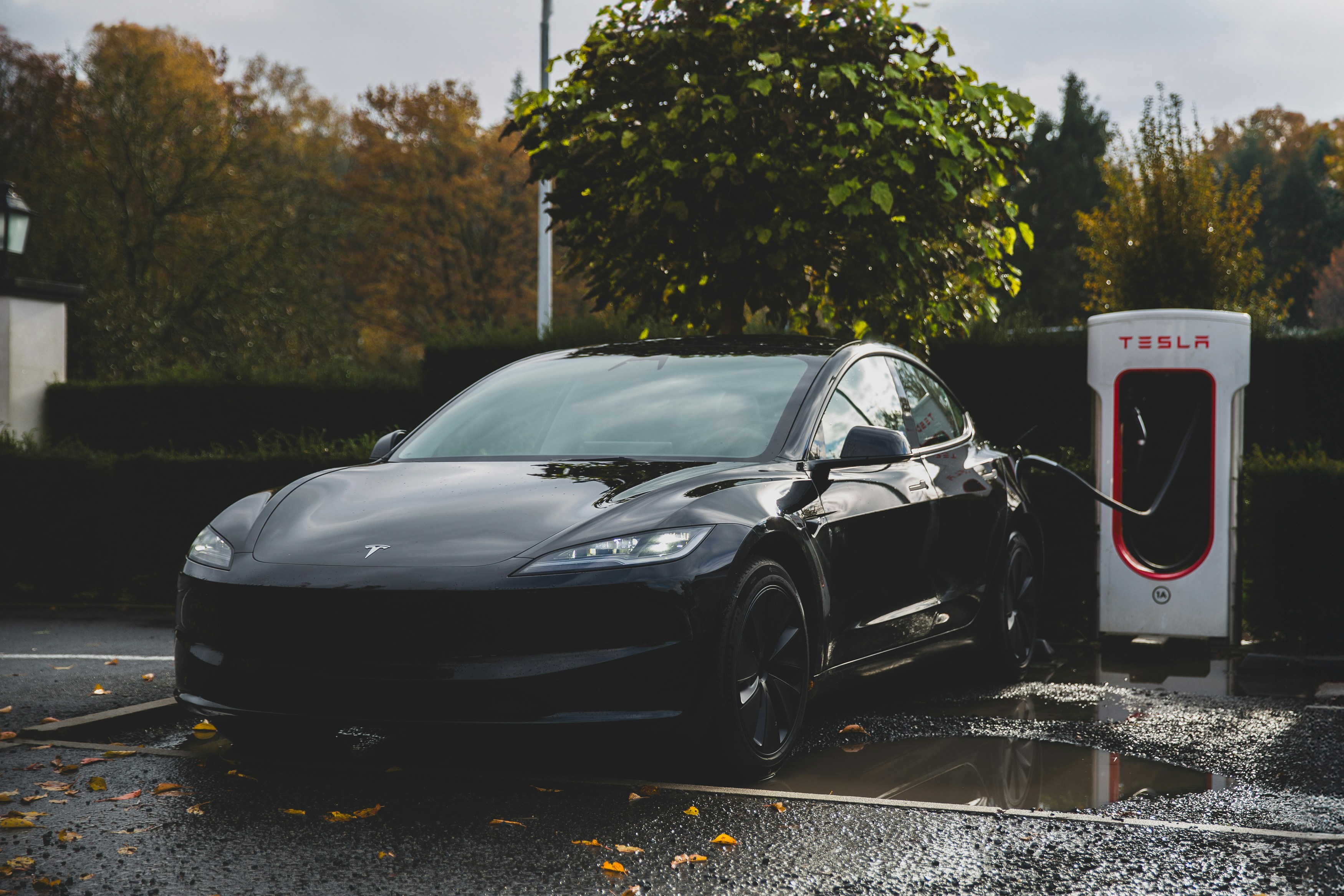 Tesla vehicles charging at a Supercharger station along a New Jersey highway