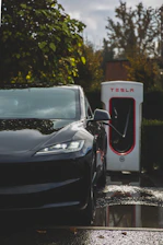 Electric vehicle charging station at sunset with green and black branding elements.
