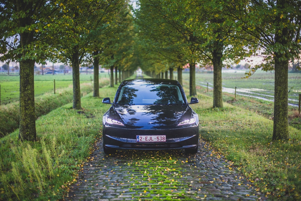 a black car parked on a cobblestone road