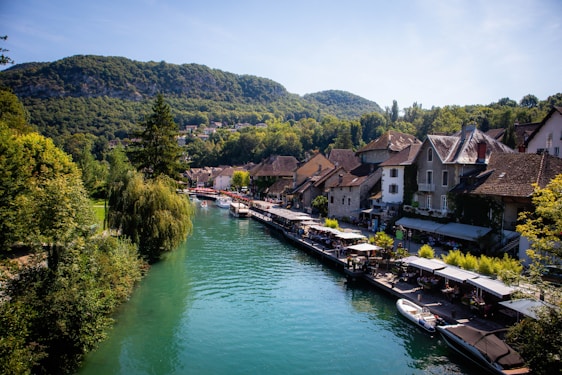 A peaceful riverfront view with cozy cottages, green lawns, and a small café by the water.