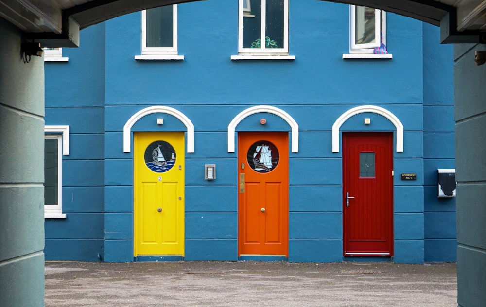 a row of brightly colored doors in front of a blue building