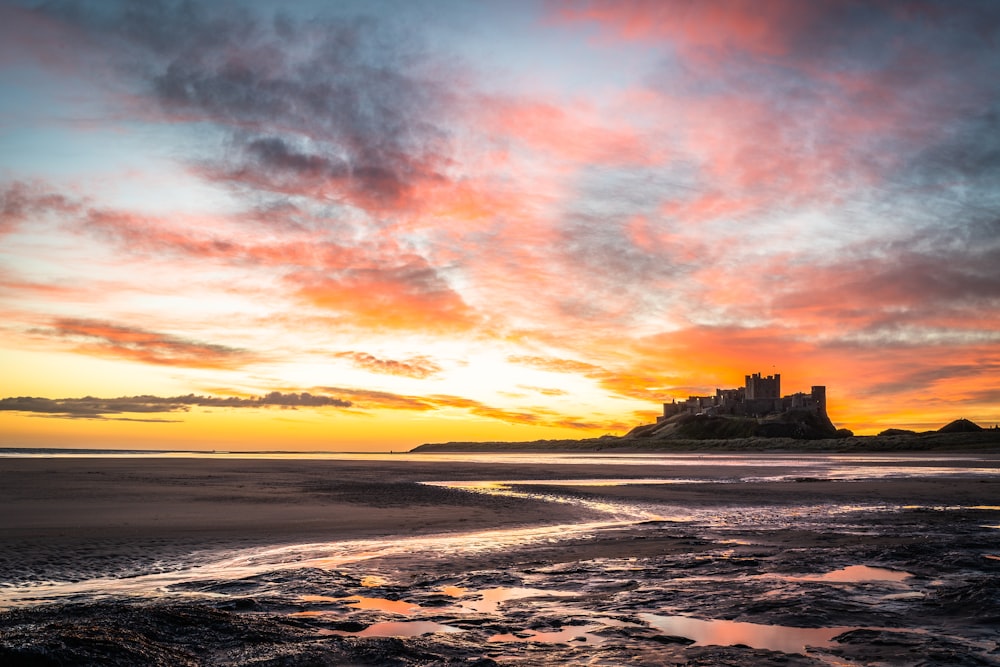 a castle sits in the distance as the sun sets