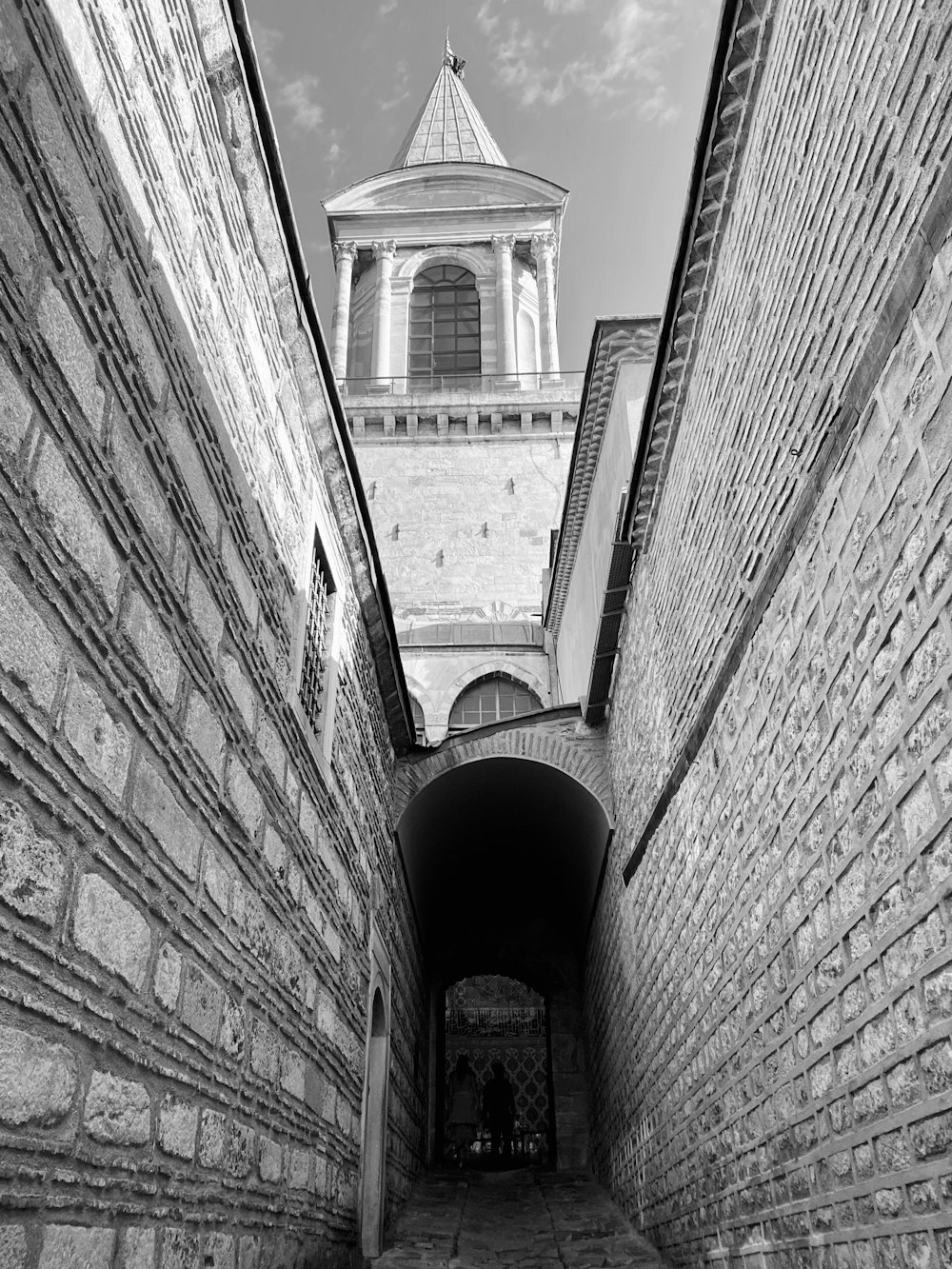 Una foto en blanco y negro de un túnel con una torre de reloj al fondo