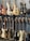 A collection of electric and bass guitars hanging on display racks. The guitars vary in color, shape, and design, showcasing a range of wood finishes and hardware styles.