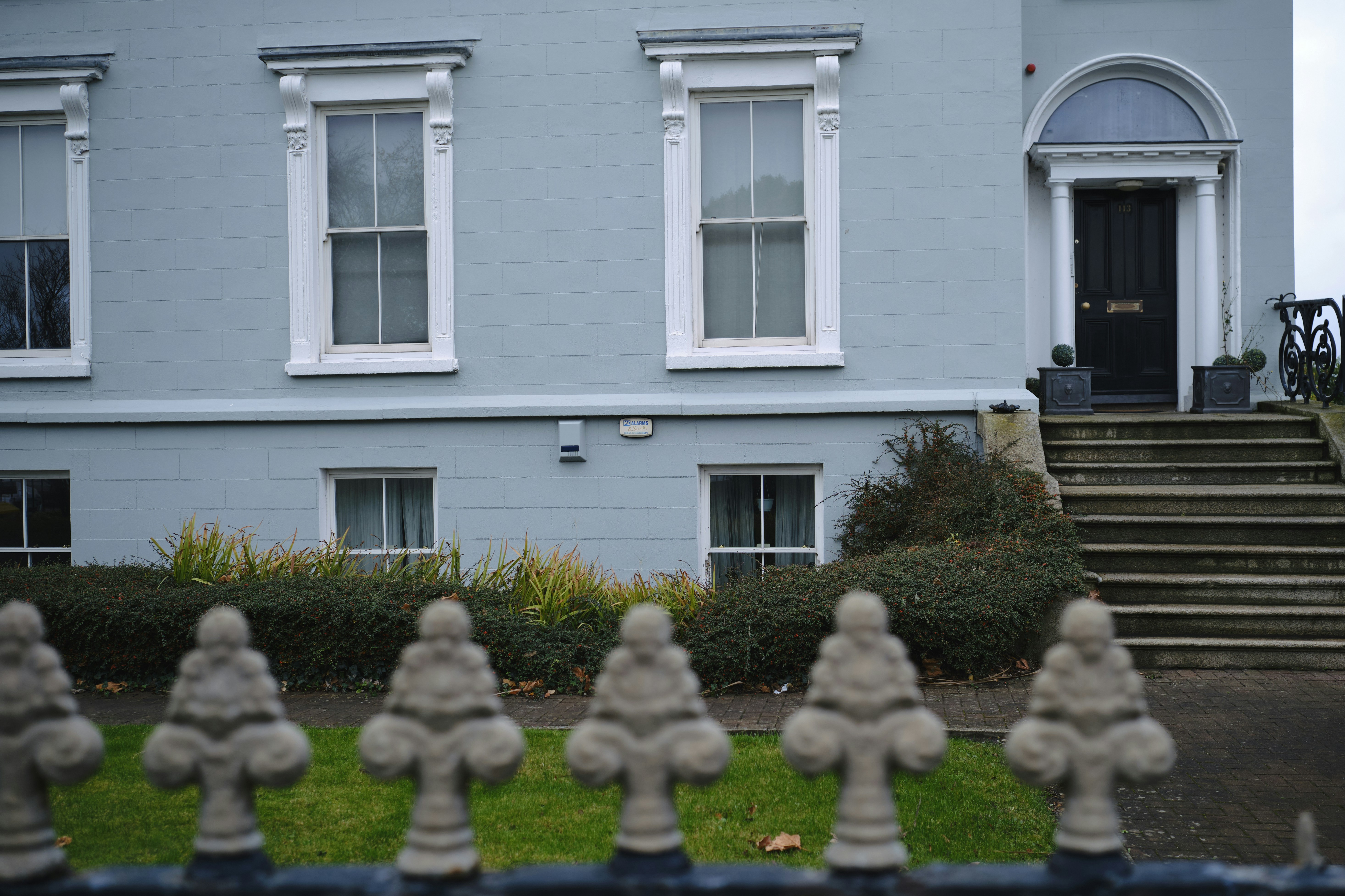 a blue house with white windows and a black gate
