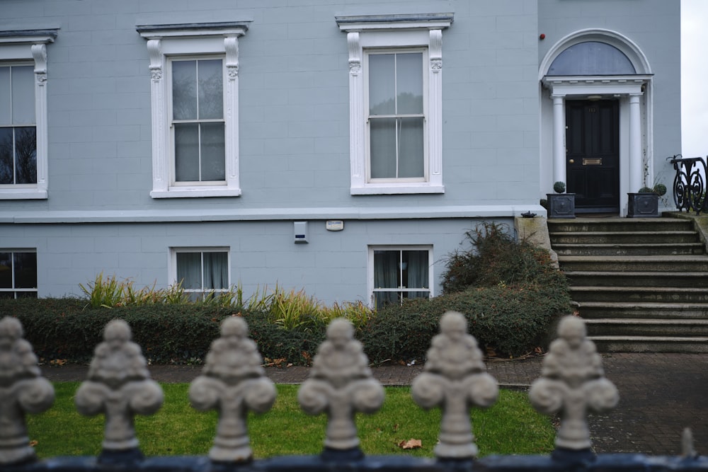 a blue house with white windows and a black gate