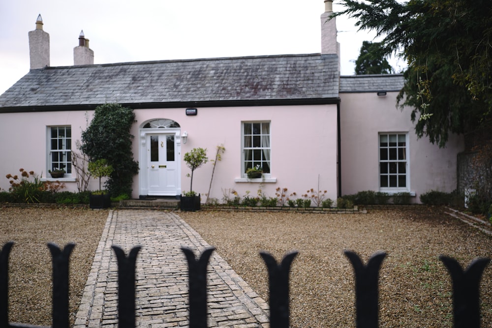 a pink house with a white door and a black fence